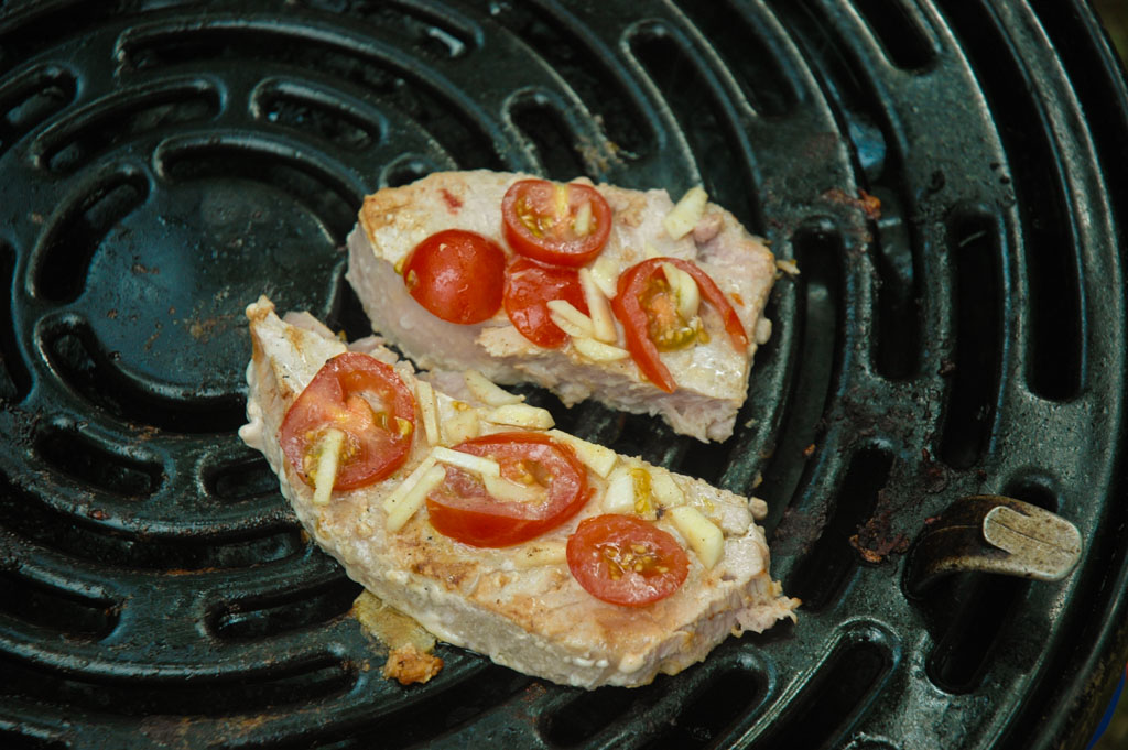 Verse tonijnfilet met tomaat, knoflook en kruiden op de grill van de skottel.