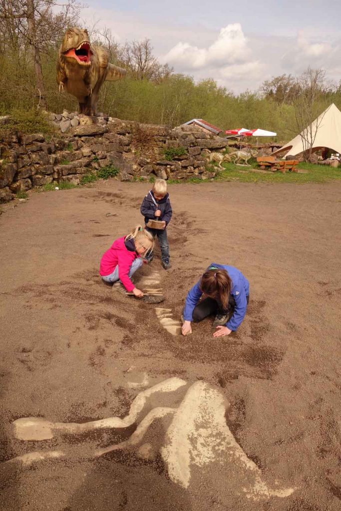 De kinderen graven een dinoskelet uit.